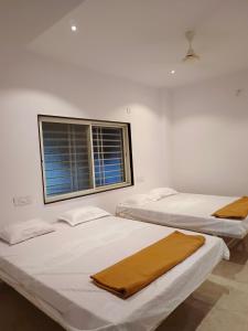 two beds in a room with a window at Laxmi Residency in Akalkot