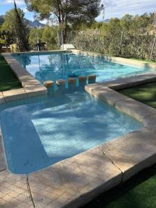a swimming pool with blue water and stools in it at Casas Rurales La Navela in Blanca +16 photos