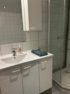 a white bathroom with a sink and a shower at City home in Tromsø