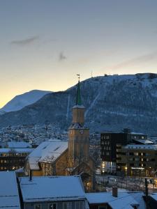 a building with a clock tower with a mountain in the background at City home in Tromsø