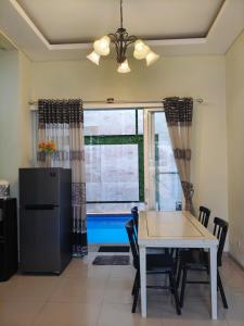 ein Esszimmer mit Tisch und Stühlen und einem Fenster in der Unterkunft Villa Gamelas Kusuma Pinus Batu in Batu