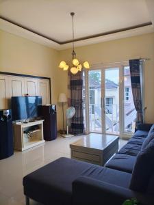 ein Wohnzimmer mit einem blauen Sofa und einem Fernseher in der Unterkunft Villa Gamelas Kusuma Pinus Batu in Batu