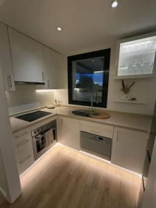 eine Küche mit weißen Schränken und einer Spüle und einem Fenster in der Unterkunft Corvera Golf Lexu in Corvera