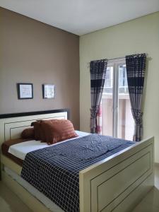 ein Schlafzimmer mit einem Bett und einem Fenster mit Vorhängen in der Unterkunft Villa Gamelas Kusuma Pinus Batu in Batu + 11 Fotos