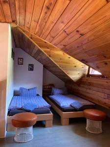 two beds in a room with a wooden ceiling at Penzion u Zdichynců in Kubova Huť