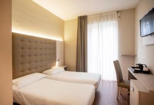 a hotel room with two beds and a window at Primavera in Stresa