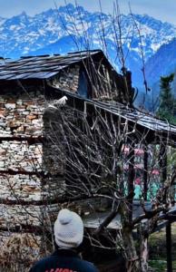 Un hombre parado frente a una casa con una montaña cubierta de nieve. en Magic moments homestay, en Kasol 5 fotos más