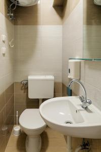 a bathroom with a white toilet and a sink at Clementine Apartman in Százhalombatta