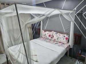 1 cama blanca con dosel en una habitación en Silantoi hotel, en Gatunga