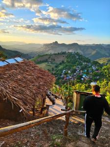 Un homme debout sur une colline en regardant un village dans l'établissement Homestay Nunga หนูหง่าโฮมสเตย์, à Mae Hong Son