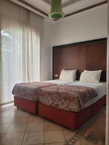 马拉喀什Palmeraie village 2 , les jardins de la palmeraie 2的卧室里有一张带木质床头板的大床