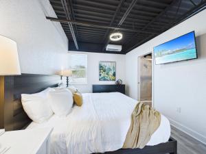 une chambre avec un lit blanc et une télévision dans l'établissement Sleek Coastal Loft Close To Port & Beach -unit 205, à Cap Carnaveral