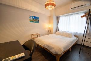 a bedroom with a bed and a desk and a window at Yokosuka Royal Bari House 703 in yokosuka chuo station in Yokosuka