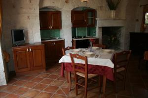 cocina con mesa y sillas y TV en Masseria La Luna Nel Pozzo, en Castellana Grotte