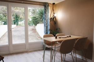 a dining room with a table and chairs and a window at Appartement Jungle Cosy - Bureau & Fibre - Proche Futuroscope in Jaunay-Marigny