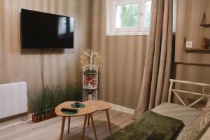a living room with a flat screen tv on the wall at Appartement Jungle Cosy - Bureau & Fibre - Proche Futuroscope in Jaunay-Marigny