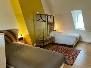 2 Betten in einem Zimmer mit gelben Wänden und einem Fenster in der Unterkunft Maison 2 chambres avec bureau - Proche gare in Saint-Omer