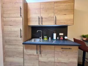 eine Küche mit Spüle und Holzschränken in der Unterkunft Maison 2 chambres avec bureau - Proche gare in Saint-Omer