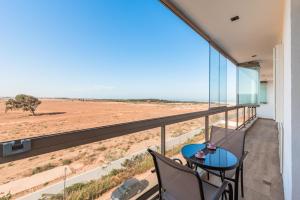 Oulad AkkouにあるAzur Apartment pool & designの砂漠の景色を望むバルコニー(テーブル、椅子付)