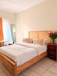 une chambre avec un grand lit avec une tête de lit en bois dans l'établissement Mini Cottage Home, à Johannesbourg