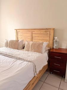 - un lit avec une tête de lit en bois à côté d'une commode dans l'établissement Mini Cottage Home, à Johannesbourg