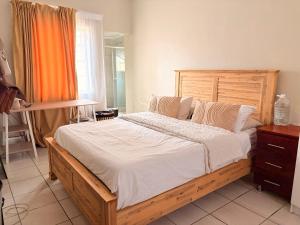 a bedroom with a large wooden bed with white sheets at Mini Cottage Home in Johannesburg