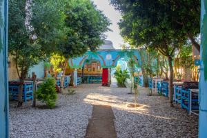 a garden with a blue building with tables and trees at Pharaohs Rest Luxor in Luxor +14 photos