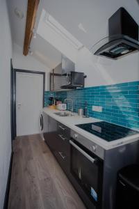 a kitchen with a stove and blue tiles on the wall at Balmoral Lodge, King Size Apartment by The Hive WA1 in Warrington