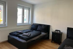 Bett in einem Zimmer mit zwei Fenstern in der Unterkunft Cozy City Center Designer Apartment for 10 People in Wiener Neustadt