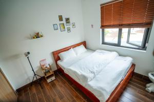 a bedroom with a bed with white sheets and a window at Dimori homestay in Thôn Trường Giang