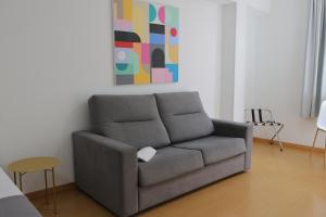 eine graue Couch in einem Wohnzimmer mit einem Gemälde in der Unterkunft Hotel Las Palmas Urban Center in Las Palmas de Gran Canaria + 5 Fotos