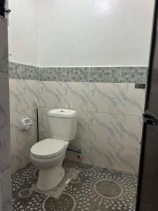 a bathroom with a toilet and a tiled wall at Dean's Homestay Siargao in General Luna