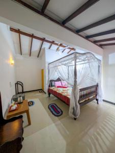 a bedroom with a bed with a mosquito net at Samudra Guest House in Mirissa
