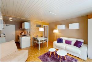 a living room with a white couch and a kitchen at Studio à Morgins in Troistorrents