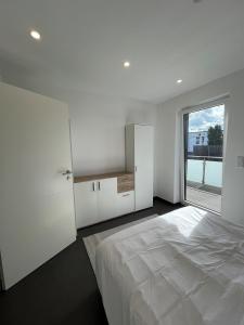 a white bedroom with a large bed and a window at Modern new-build apartment in Groß-Gerau