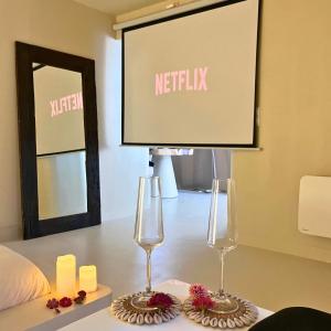 deux verres à vin posés sur une table devant un écran dans l'établissement Casa Cinta - Sanctuaire Balinais avec Baignoire Balnéo et Cinéma Privé, à Croix