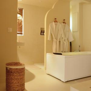 La salle de bains est pourvue d'un peignoir blanc sur un miroir. dans l'établissement Casa Cinta - Sanctuaire Balinais avec Baignoire Balnéo et Cinéma Privé, à Croix