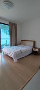 ein Bett in einem Zimmer mit einem großen Fenster in der Unterkunft Superb hotel apartment in Gelang Patah