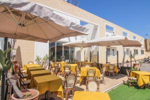 eine Terrasse mit gelben Tischen, Stühlen und Sonnenschirmen in der Unterkunft Hotel Paladini di Francia in Lampedusa