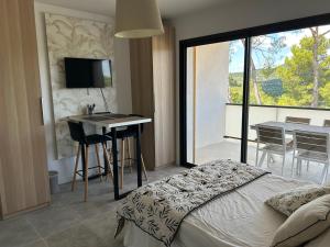 une chambre avec un lit et un bureau et un balcon dans l'établissement Au Pied du Pic Saint Loup, à Saint-Mathieu-de-Tréviers