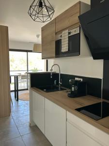 une cuisine avec des armoires blanches, un évier et une cuisinière dans l'établissement Au Pied du Pic Saint Loup, à Saint-Mathieu-de-Tréviers