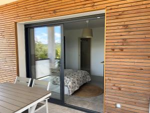une chambre avec un lit et une porte vitrée avec une table dans l'établissement Au Pied du Pic Saint Loup, à Saint-Mathieu-de-Tréviers