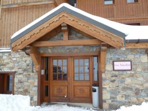 a building with a wooden door with snow on top at Les Airelles A21 in Les Menuires