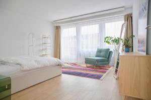 a bedroom with a bed and a chair and a window at Central rooftop apartment with AC and city view in Basel