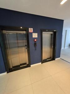 two elevators in a building with blue walls at Polo NEXT Studios in Volta Redonda