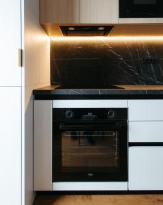 a black oven in a kitchen with white cabinets at Campus - Palas Moonlight in Iaşi +3 photos