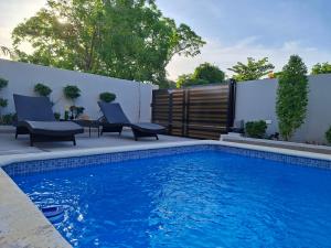 a swimming pool with two chairs next to a fence at Hermosa villa familiar cucu's home beach in Río San Juan
