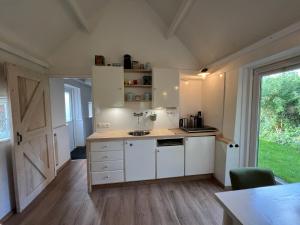 a kitchen with white cabinets and a large window at Diedjestee in Westdorp