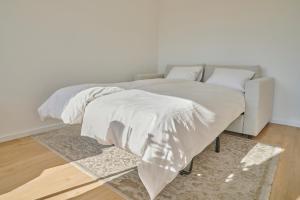 a bed with white sheets and pillows on it at Central rooftop apartment with AC and city view in Basel +7 photos