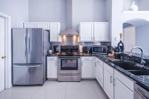 a kitchen with white cabinets and a stainless steel refrigerator at Casa Kissimmee in Orlando